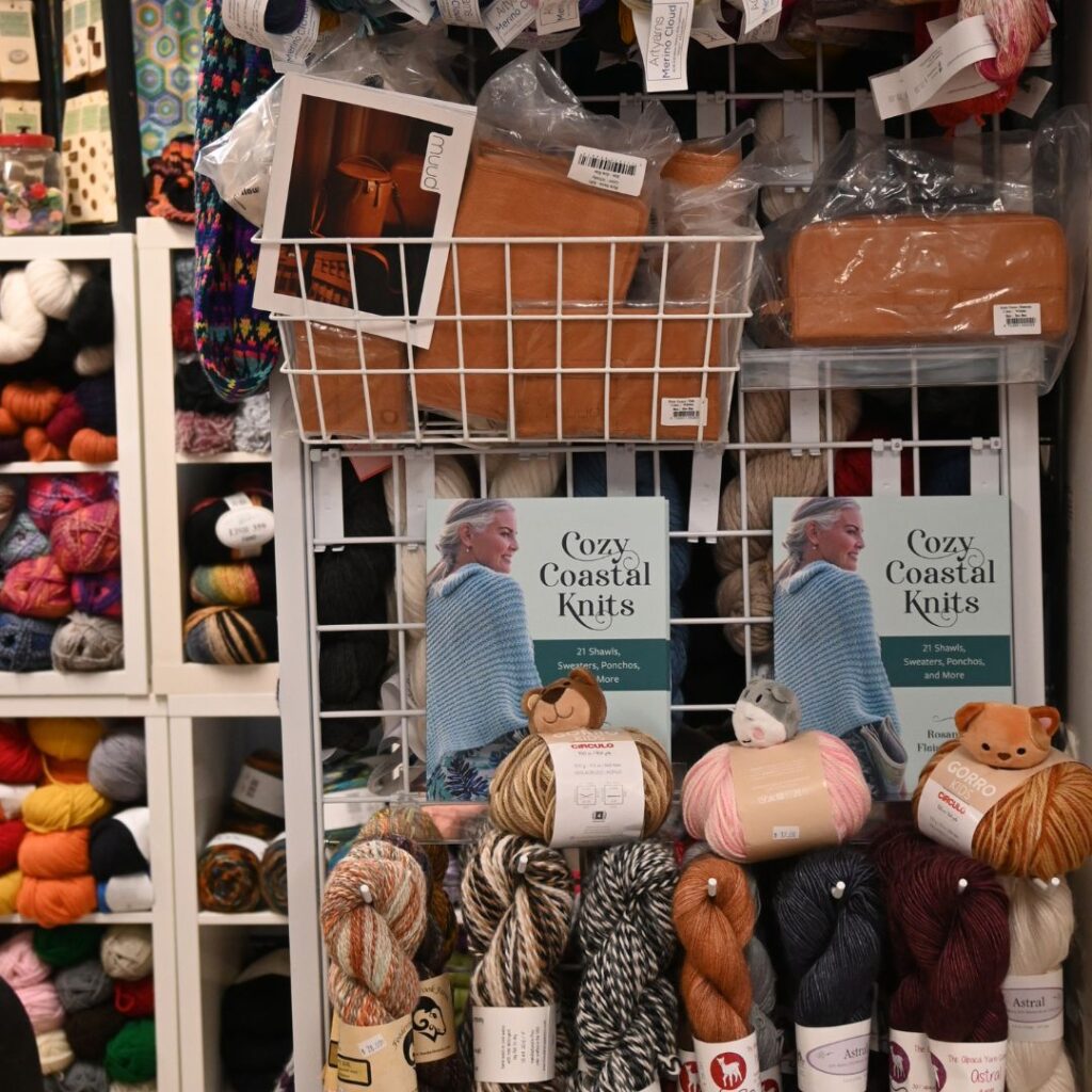 Cozy Coastal Knits sitting on. the shelves with array of yarns pink cirulio cerillo bear tiger hand dyed
